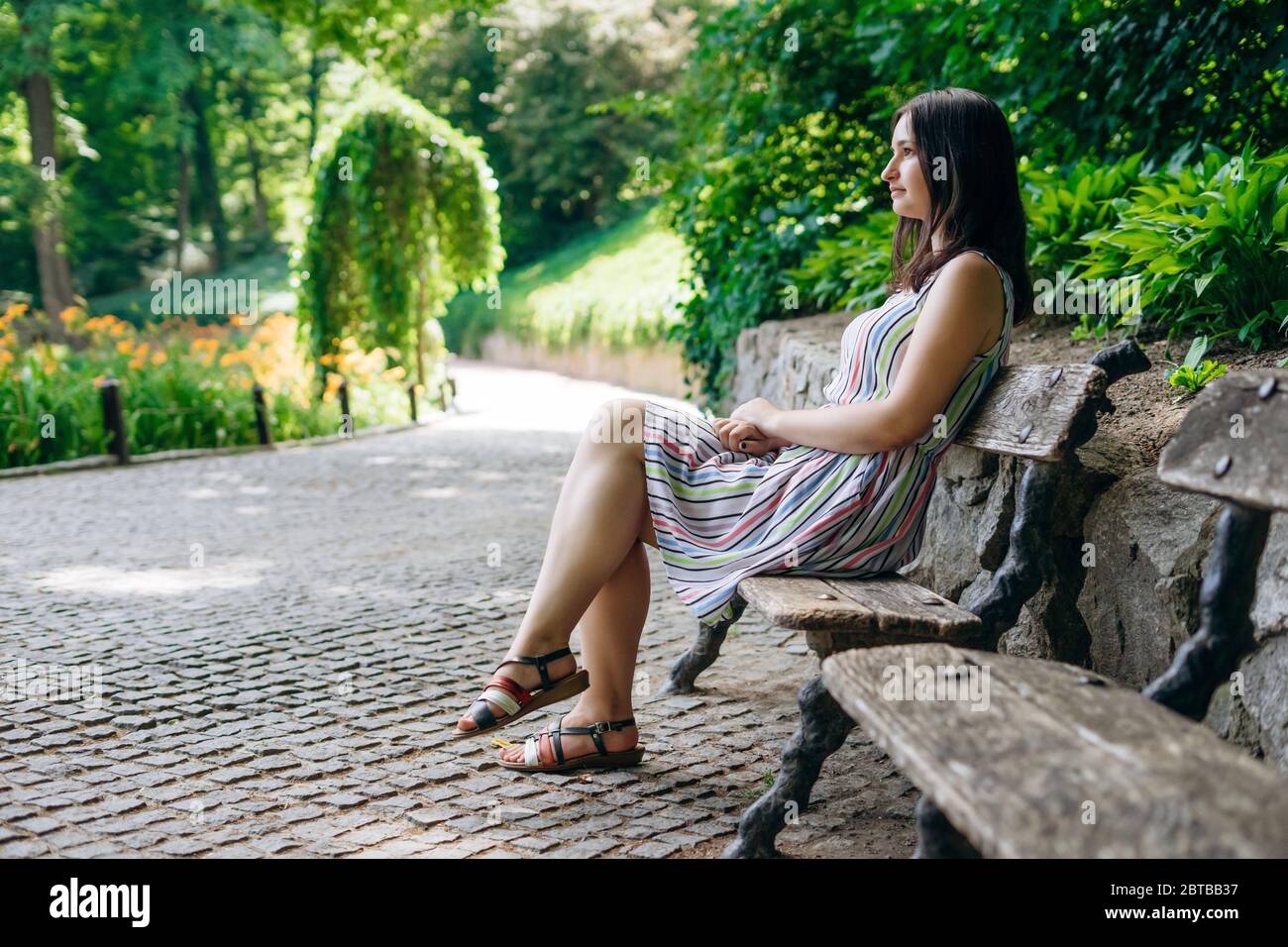 Sofia Park, Uman. Girl tourist in a summer white dress in a beautiful green  park. Girl sitting on a wooden bench in a landscaped park. Smiling girl re  Stock Photo - Alamy