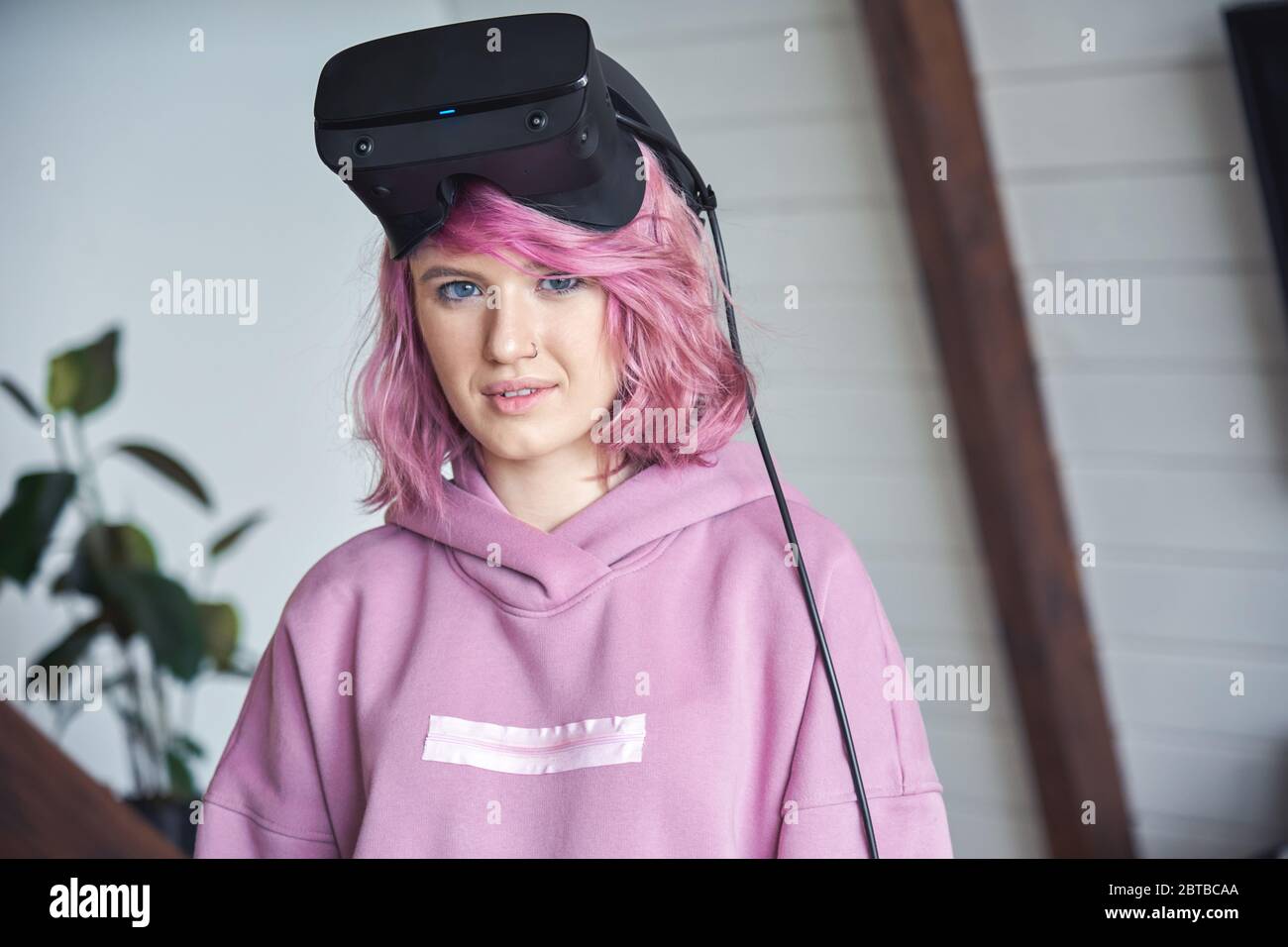Hipster teen girl with pink hair wearing vr headset on head looking at camera. Stock Photo