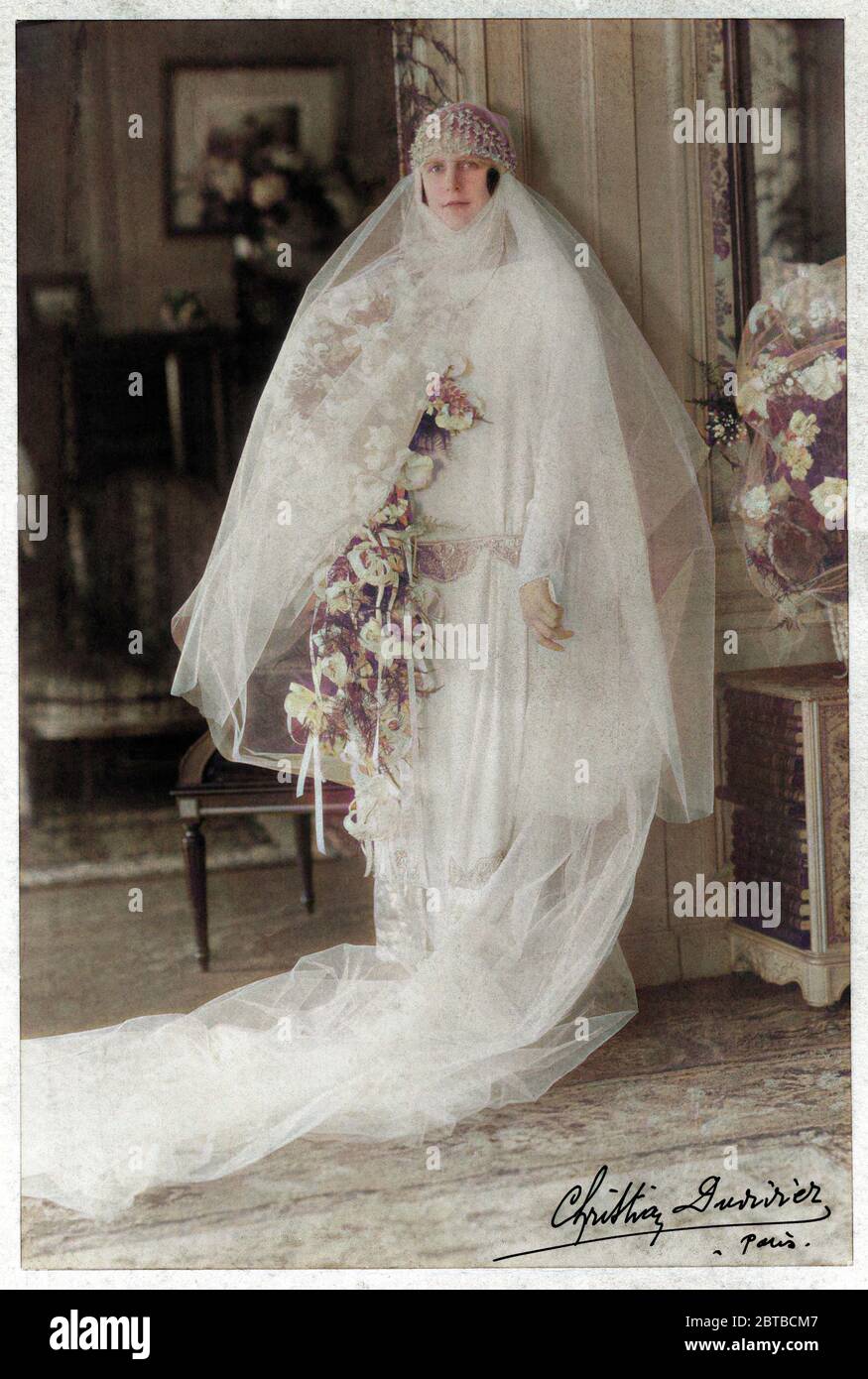 1920 ca , Paris , FRANCE : A noble woman in wedding dress attire . Photo by Christian Duvivier , Paris . The photograph Duvivier was the father of most celebrated french movie director Julien Duvivier ( 1896 - 1967 ) . DIGITALLY COLORIZED . - MARRIAGE - MATRIMONIO - NOZZE - abito da SPOSA - WEDDING dress PARTY - BRIDE -  cerimonia   - FOTO STORICHE - HISTORY PHOTOS - STOCK  -SVIZZERA - hat - cappello - FASHION XX CENTURY - MODA NOVECENTO - hat - cappello cuffia - thulle - tulle - strascico  - FAMIGLIA - FAMILY - PARENTI - festa - party - ricevimento  - velo - veil - flowers - fiori - fiore - r Stock Photo