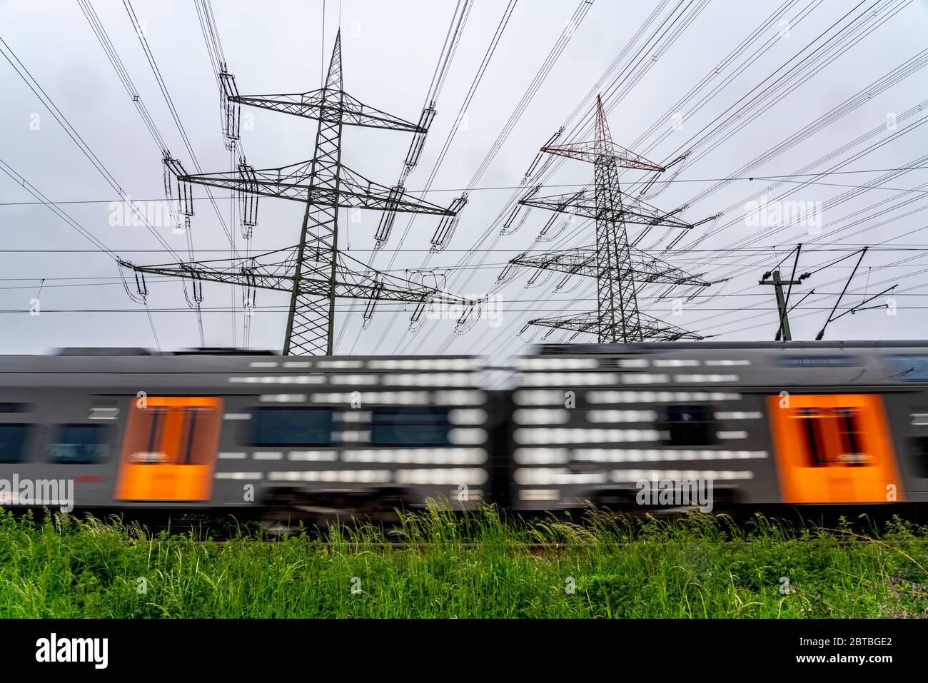 Train on the line between Essen and Bochum, power lines, extra-high voltage grid, 380 kilovolts, transports electricity generated in large power plant Stock Photo