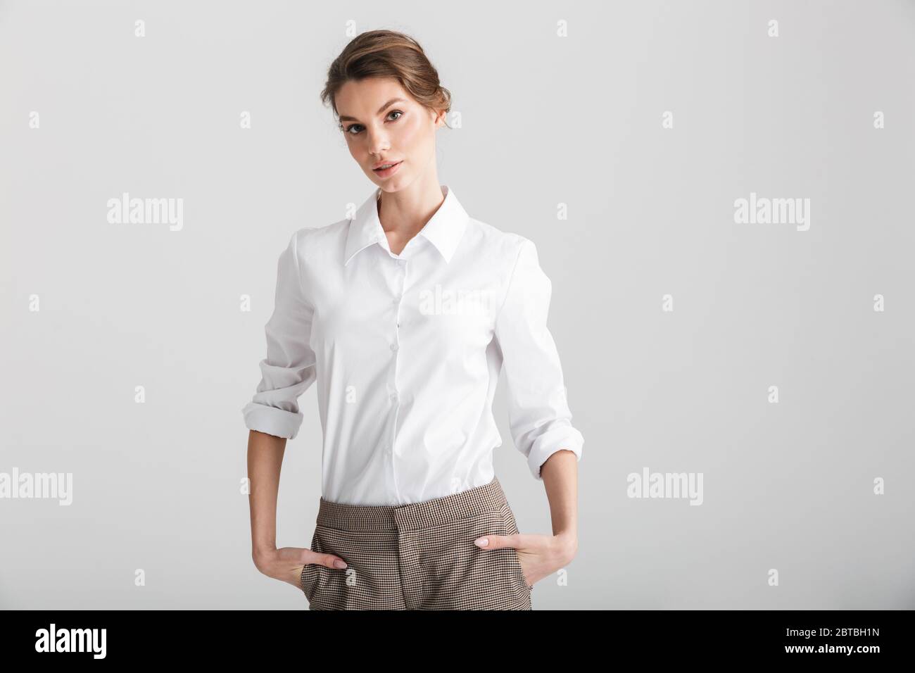 Image of young beautiful woman posing with hands in pockets isolated ...