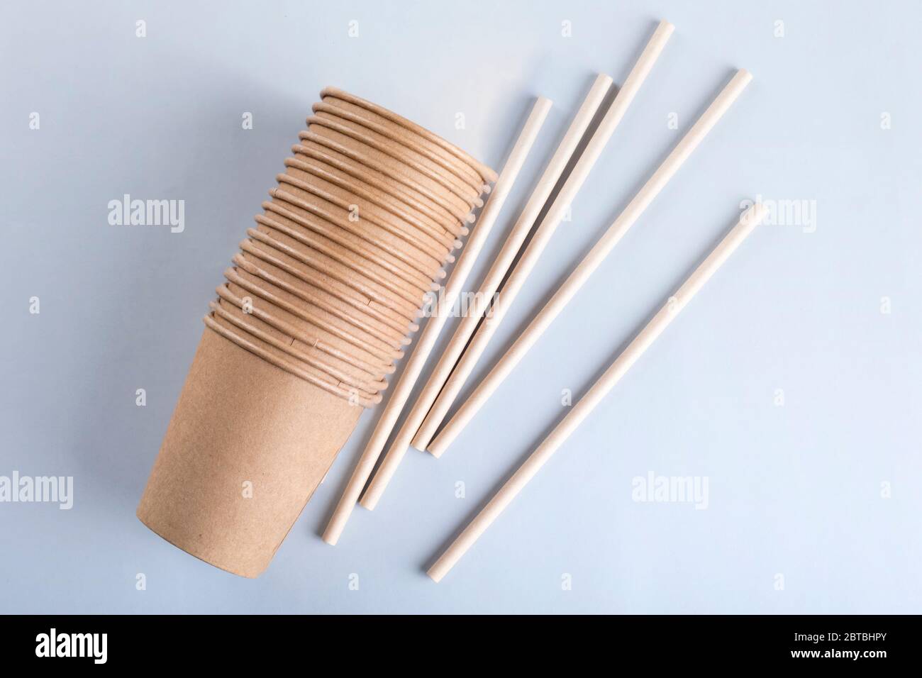Disposable cups and drinking straws on light grey background. Stock Photo