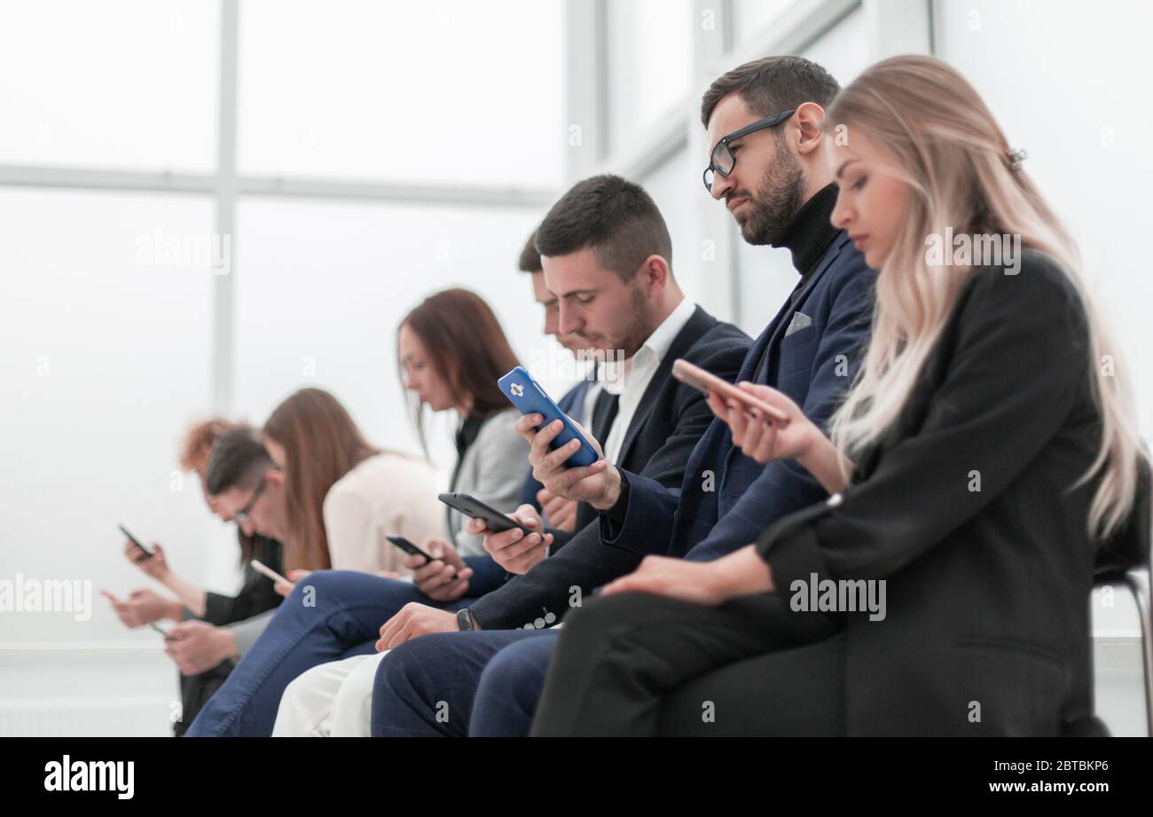 group of young business people with smartphones sitting in a row Stock ...