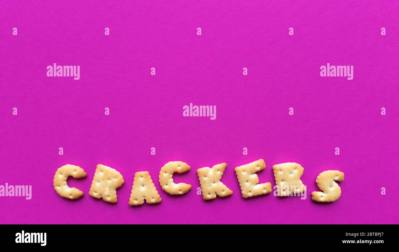 Crackers word on pink background. Simple flat lay with pastel texture