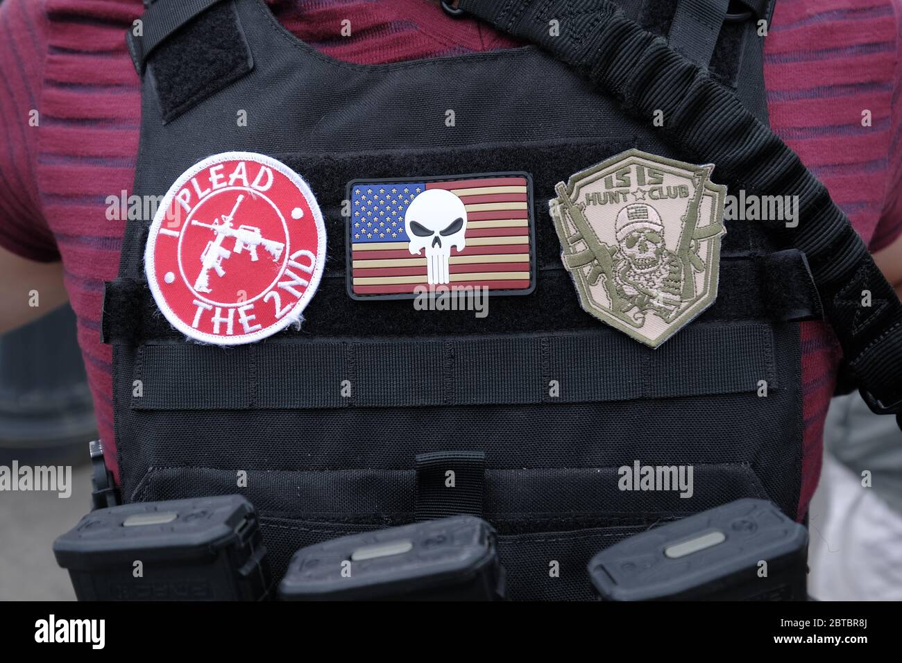 Vancouver, USA. 23rd May, 2020. A protester carrying an AR-15 assault rifle shows off his patches on a bullet-proof vest at a rally in support of the Hugga Mug Diner which re-opened today in Vancouver, Wash., on May 23, 2020. The opening is a direct violation of Governor Jay Inslee's orders for non-essential business to remain closed at this time. (Photo by Alex Milan Tracy/Sipa USA) Credit: Sipa USA/Alamy Live News Stock Photo