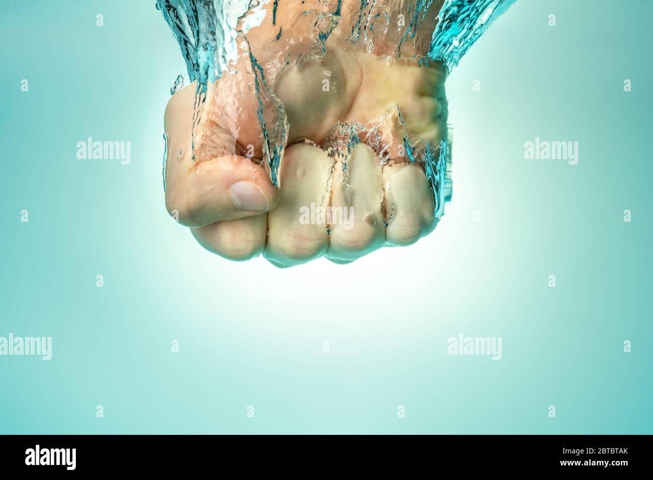 Man hit the water from above. The power of strength and self-confidence. Blue background. Stock Photo
