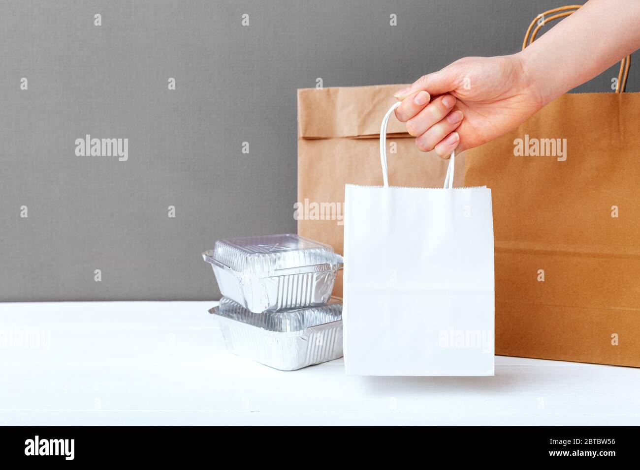 Download White Craft Paper Bag In Female Hand Delivery Mock Up Packaging Food Foil Containers And Paper Packages On Table Gray Background Food Delivery Stock Photo Alamy