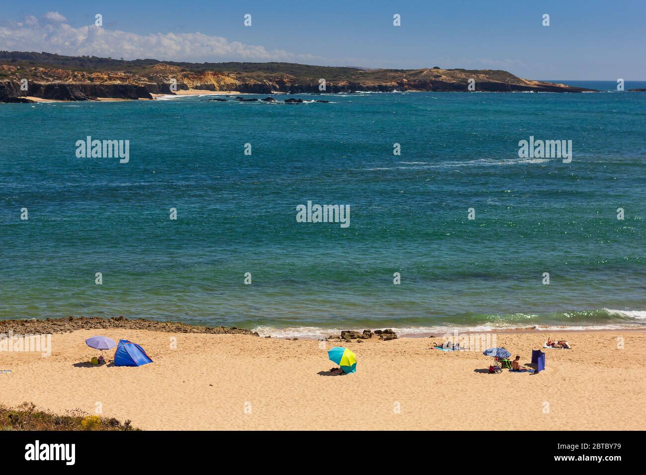 People bathing at the beach in Vila Nova de Milfontes, on hot summer day, blue sky, crystalline water Stock Photo