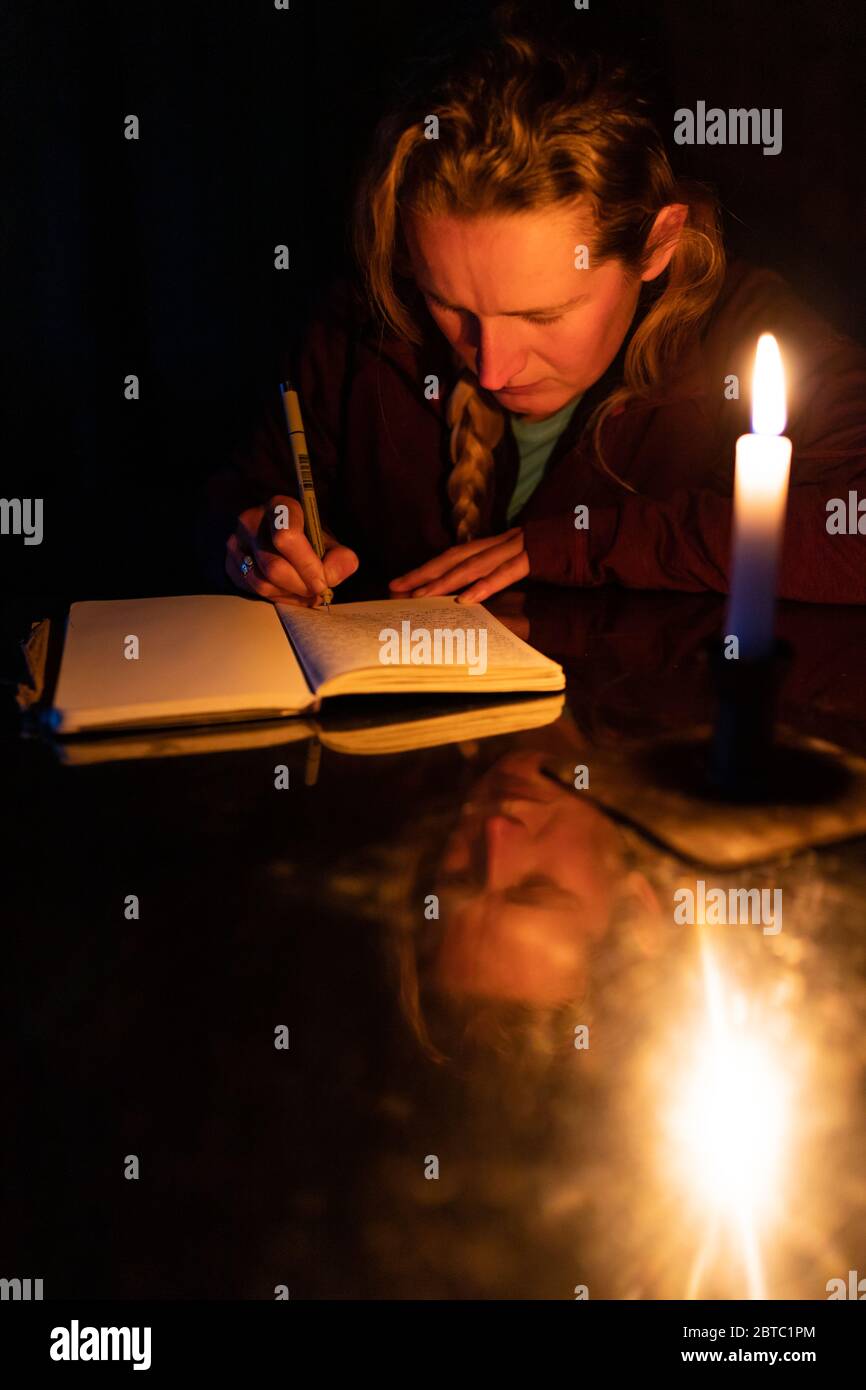 A woman writers in a journal by candlelight Stock Photo