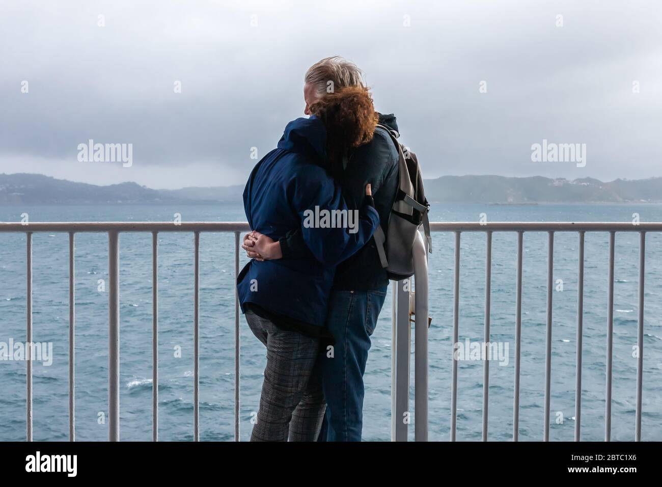 Two people embrace on the interislander ferry from Wellington to Picton, New Zealand, February 2020 Stock Photo