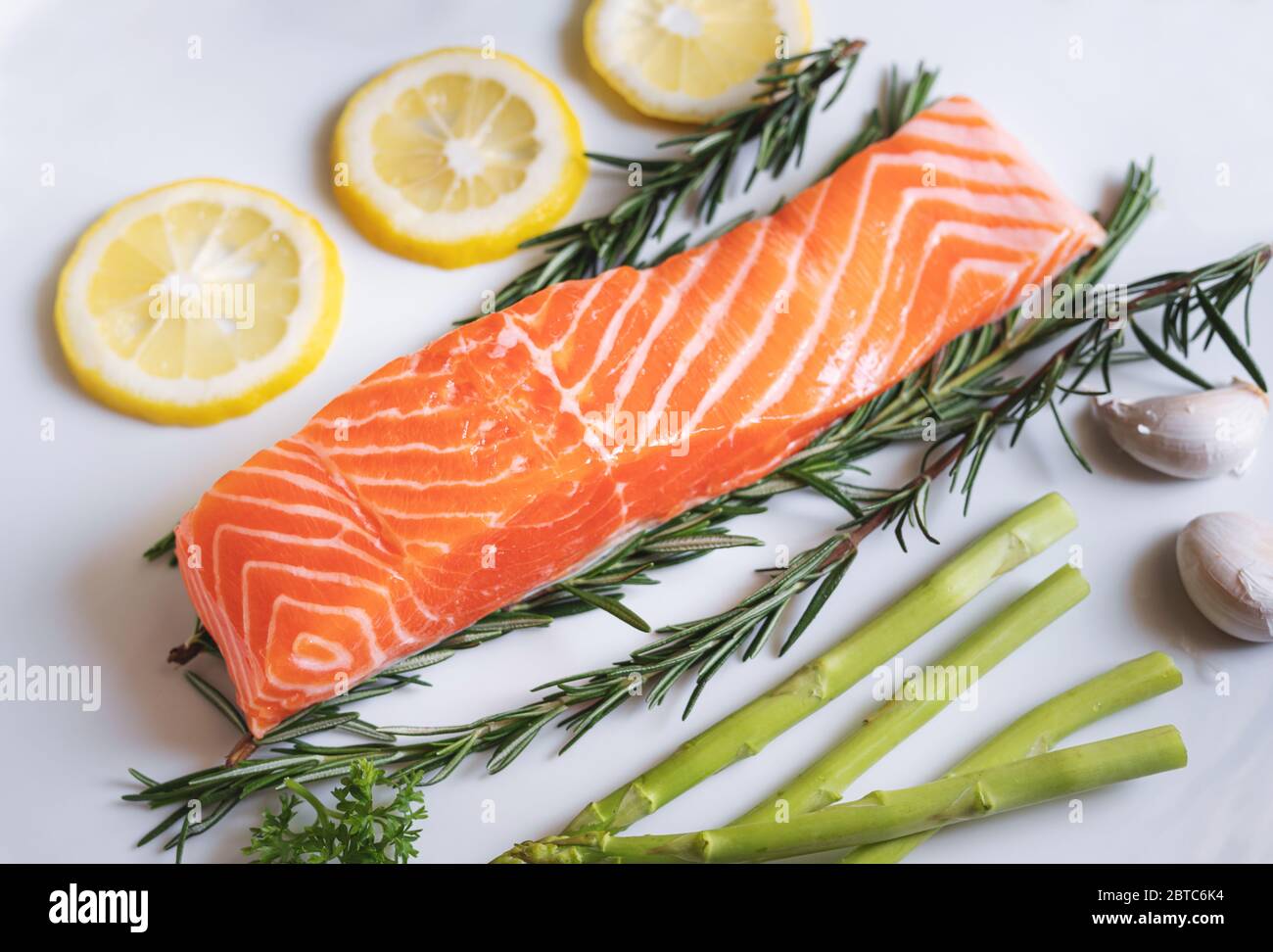 Raw fresh salmon fillet with herbs and ingredients, in white dish Stock Photo