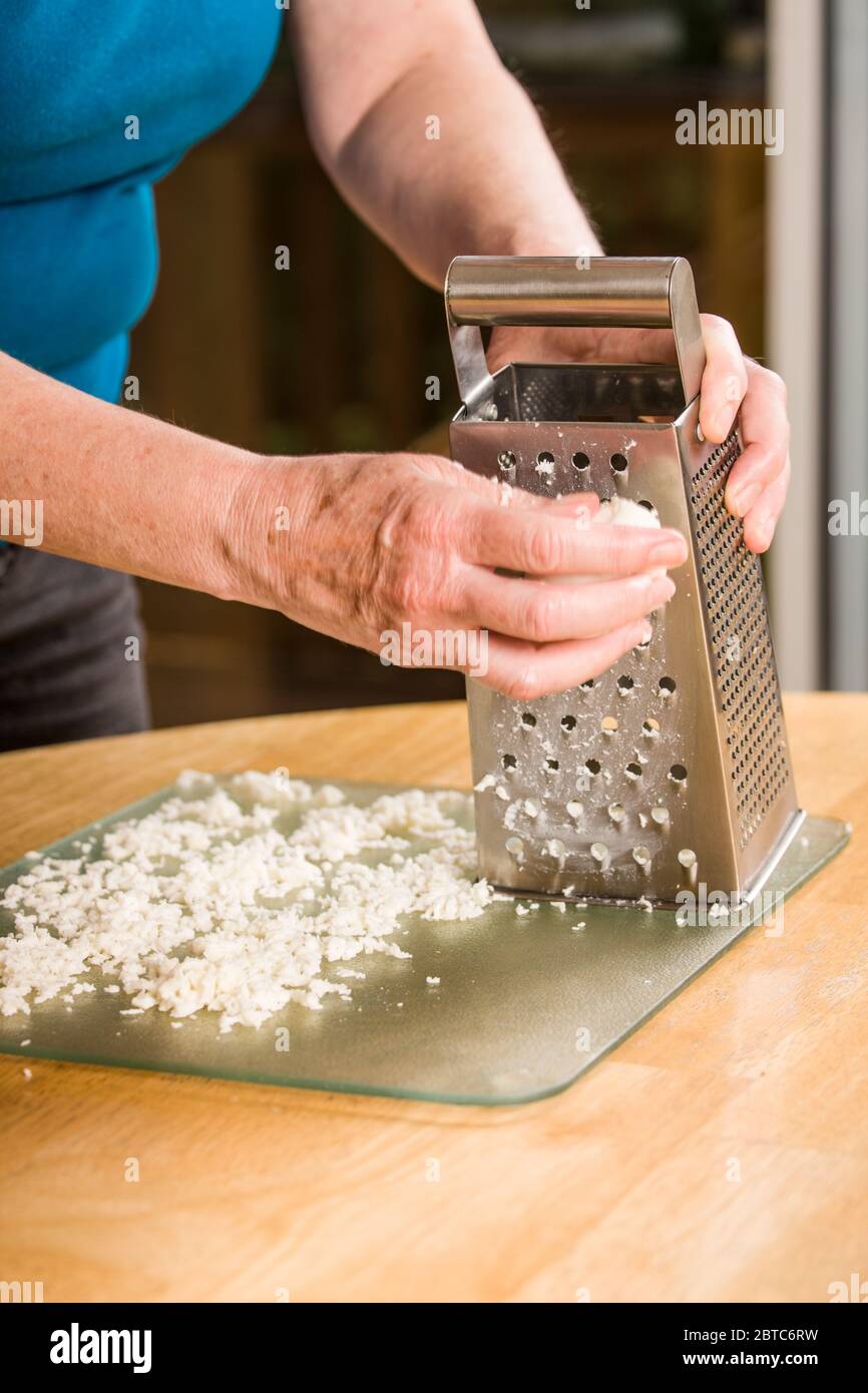 Woman grating mozzarella cheese being spread out to dry prior to being