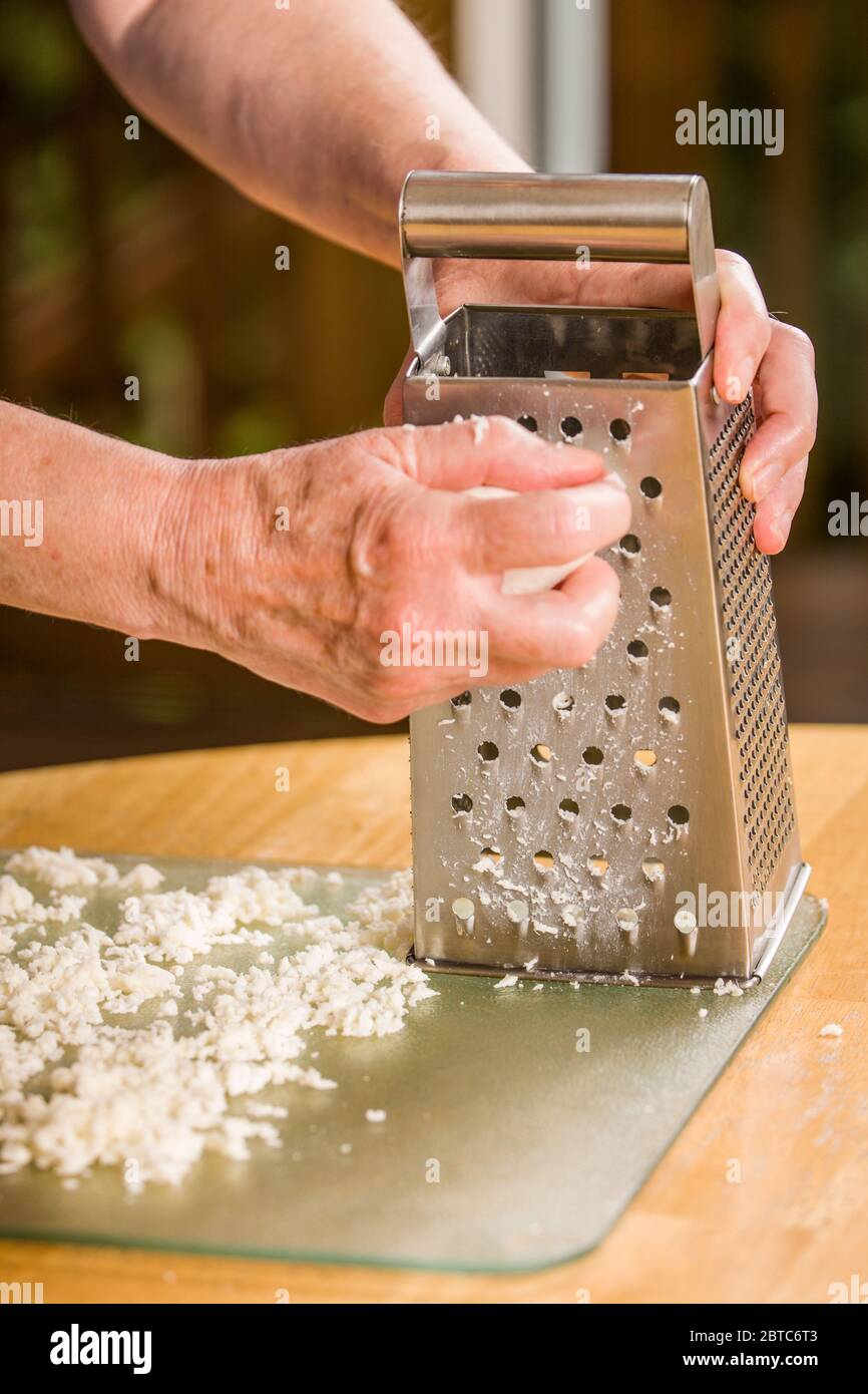 Woman grating mozzarella cheese being spread out to dry prior to being