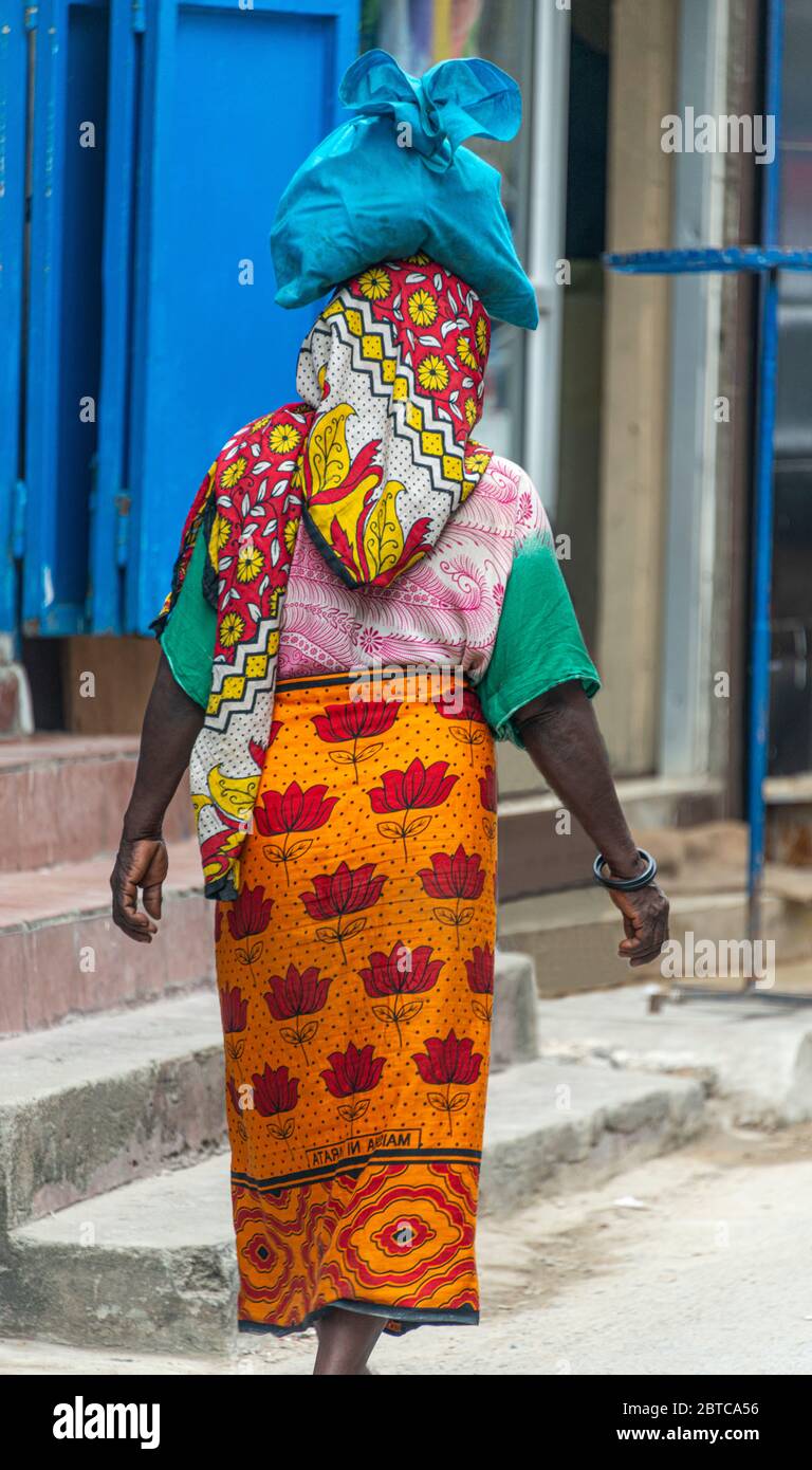Woman carrying bag on her head wearing traditional colorful clothes Stock Photo
