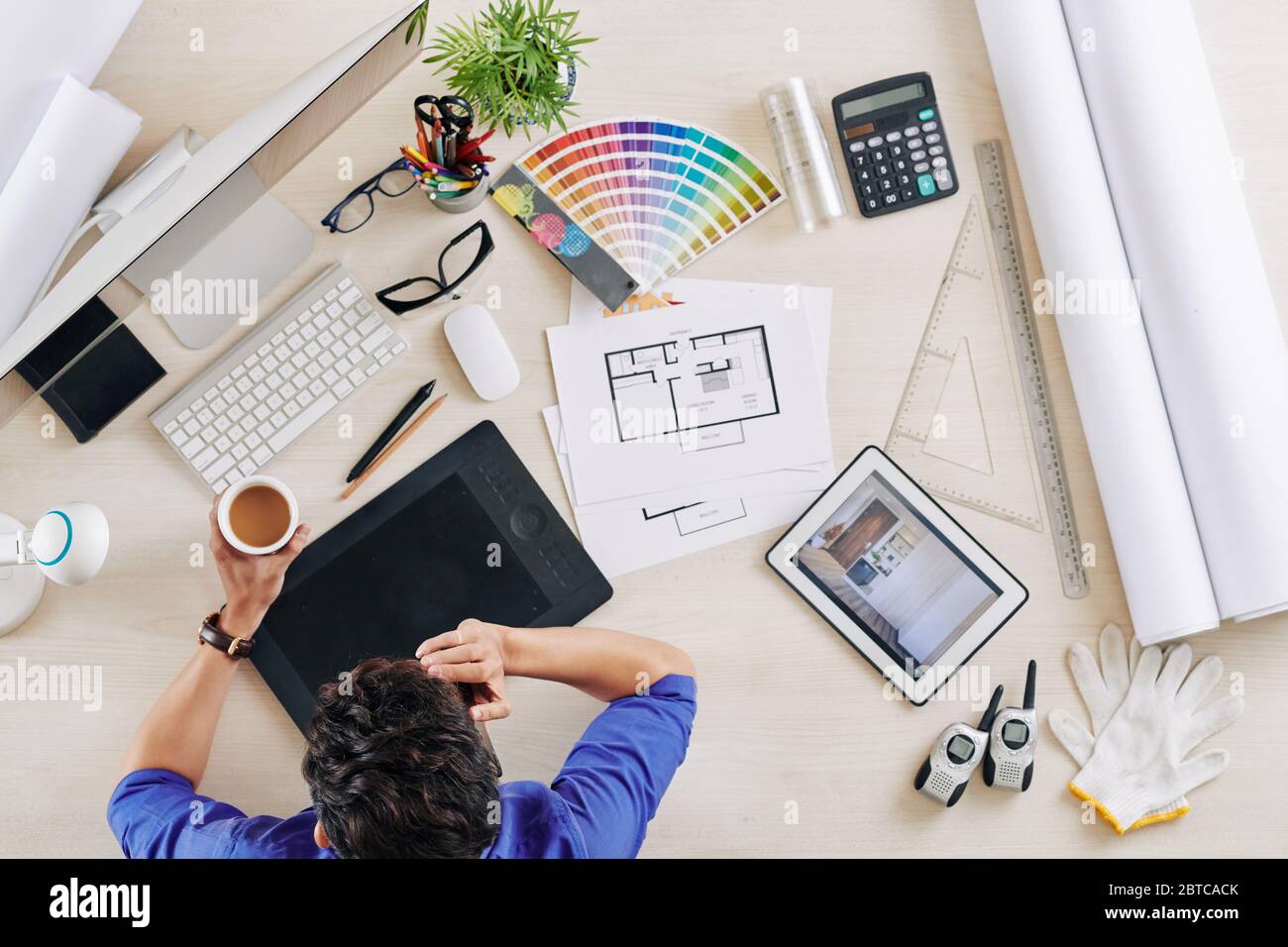 Interior designer drinking cup of coffee and talking on phone with client, view from above Stock Photo