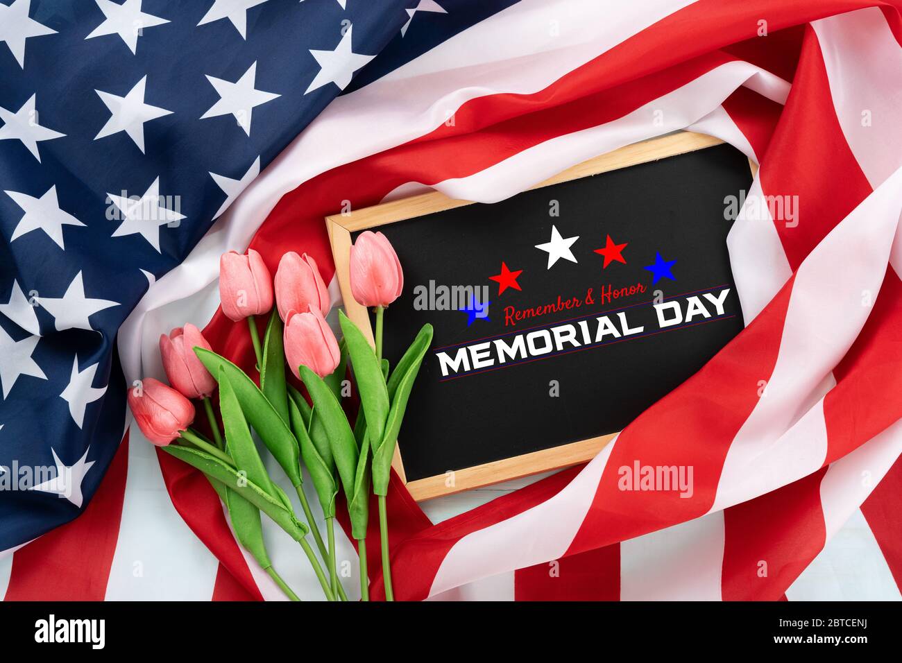 US American flag with blackboard and tulip flower on blue wooden background. For USA Memorial day. Top view with memorial day text. Stock Photo