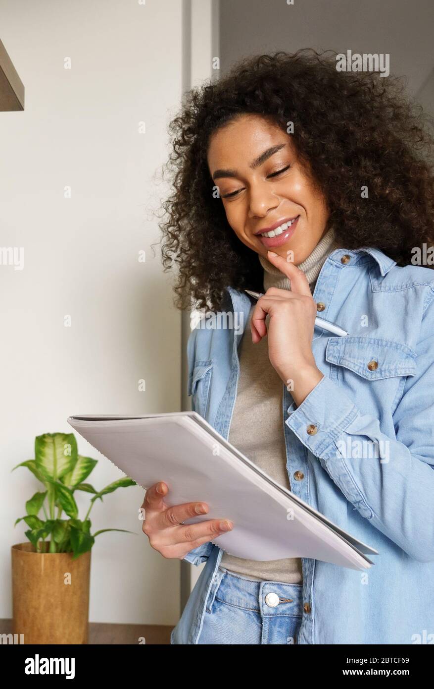 Smiling african teen girl study from home think on creative idea hold notebook. Stock Photo