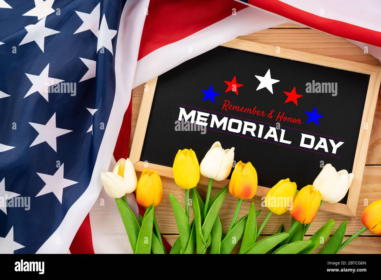 US American flag with blackboard and tulip on wooden background. For USA Memorial day. Top view with memorial day text. Stock Photo