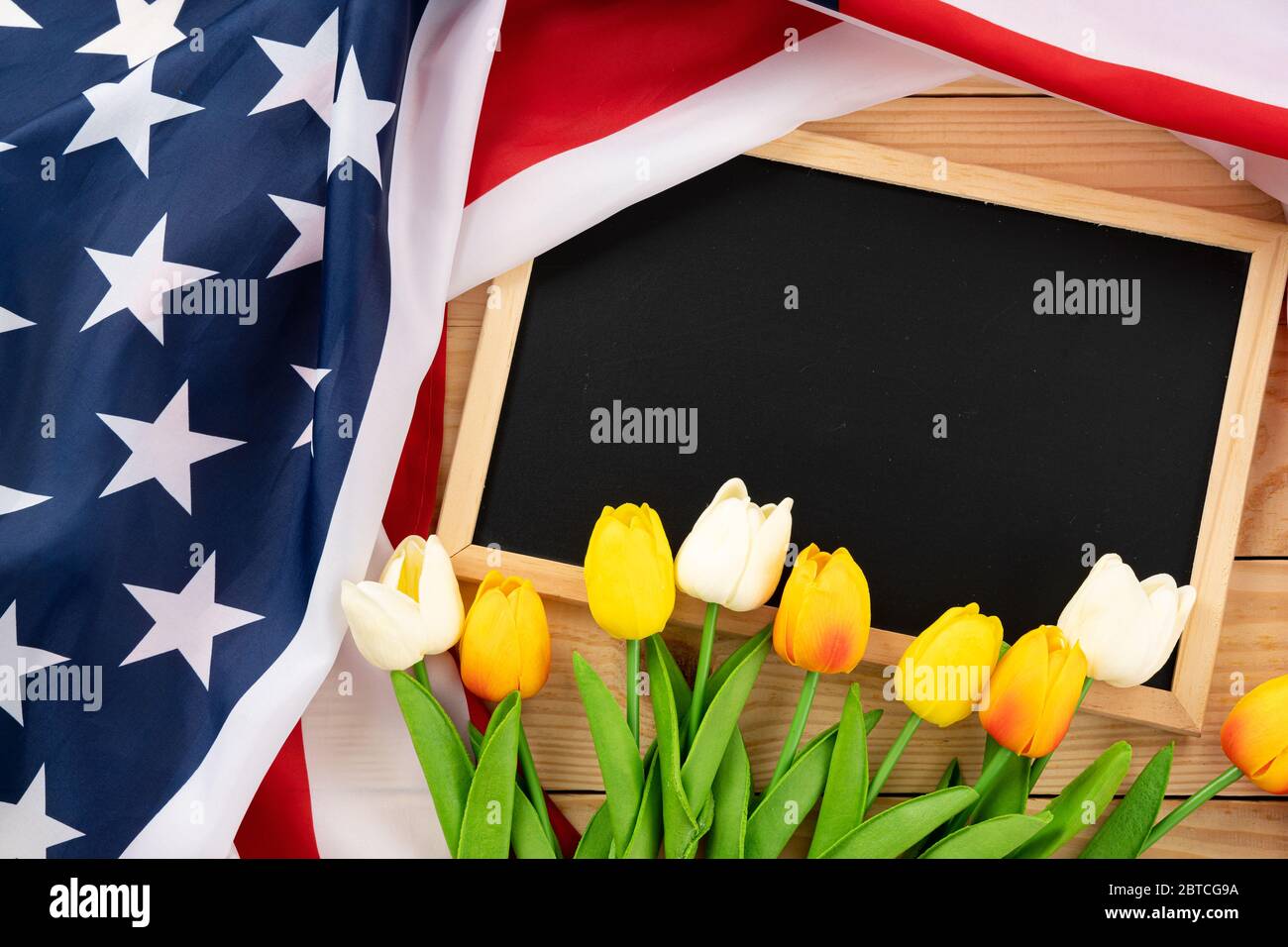 US American flag with blackboard and tulip on wooden background. For USA Memorial day, Presidents day, Veterans day, Labor day, Independence or 4th of Stock Photo