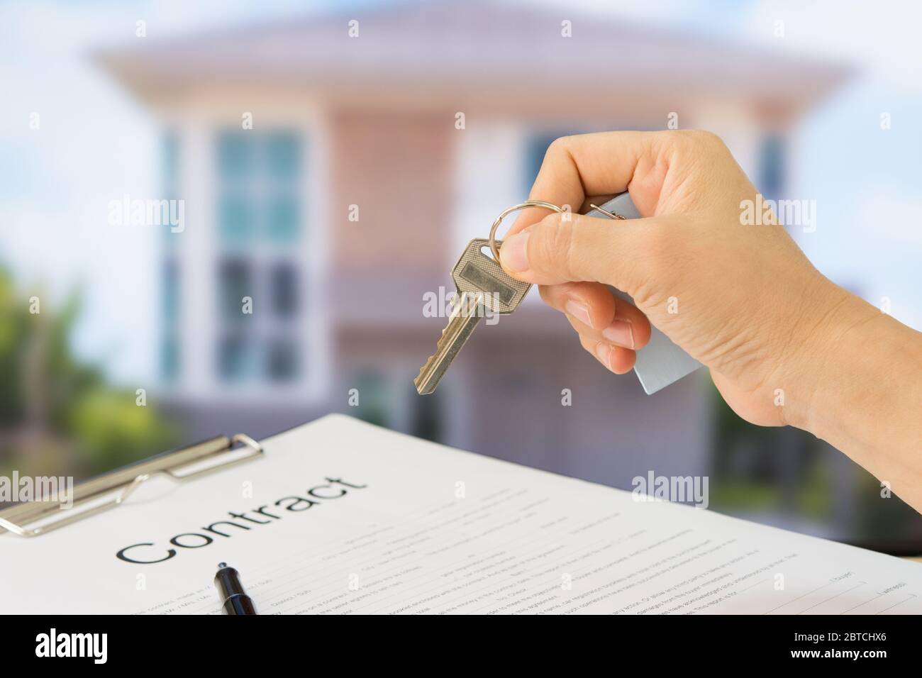 Homeowners showing house keys in front of a new home with documents