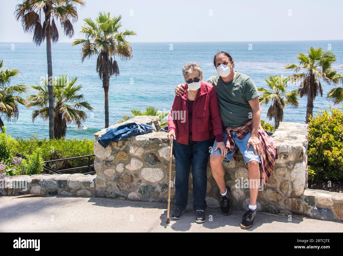 A mother of 83 with her son, aged 57, both wearing masks, on a walk in Laguna Beach, California, USA. Stock Photo