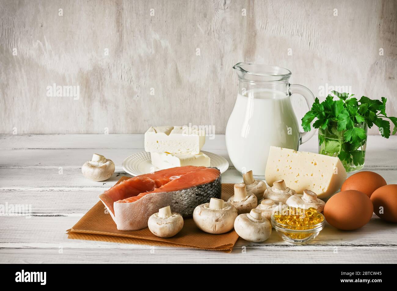 Vitamin D rich foods on a white wooden table. Natural sources of vitamin D are dairy products, salmon, egg, mushrooms, parsley, fish oil Stock Photo