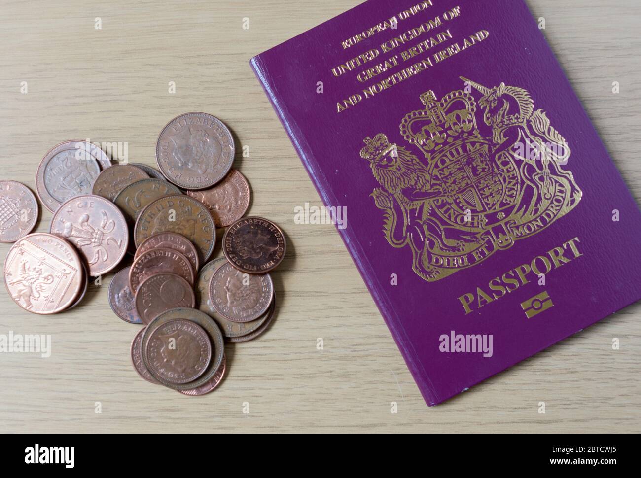 UK pennies and British passport next to each other on a table symbolising travel and savings Stock Photo