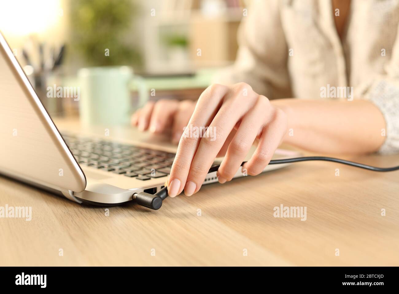 Close up of woman hands plugging battery charger on laptop at home Stock Photo