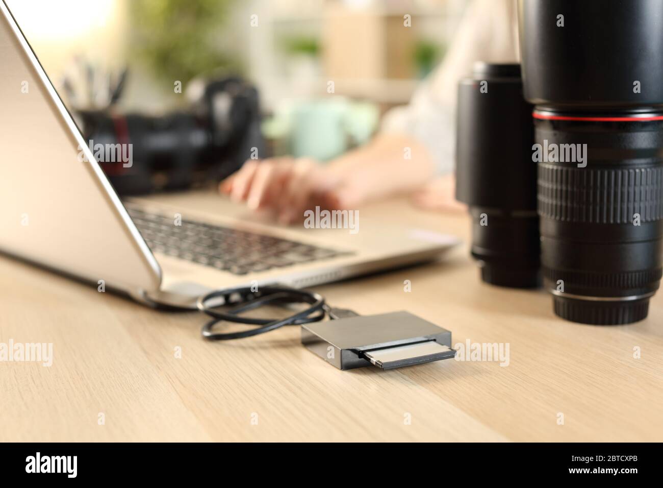 Close up of photographer woman hands transfering files from memory card to laptop on a desk at home Stock Photo