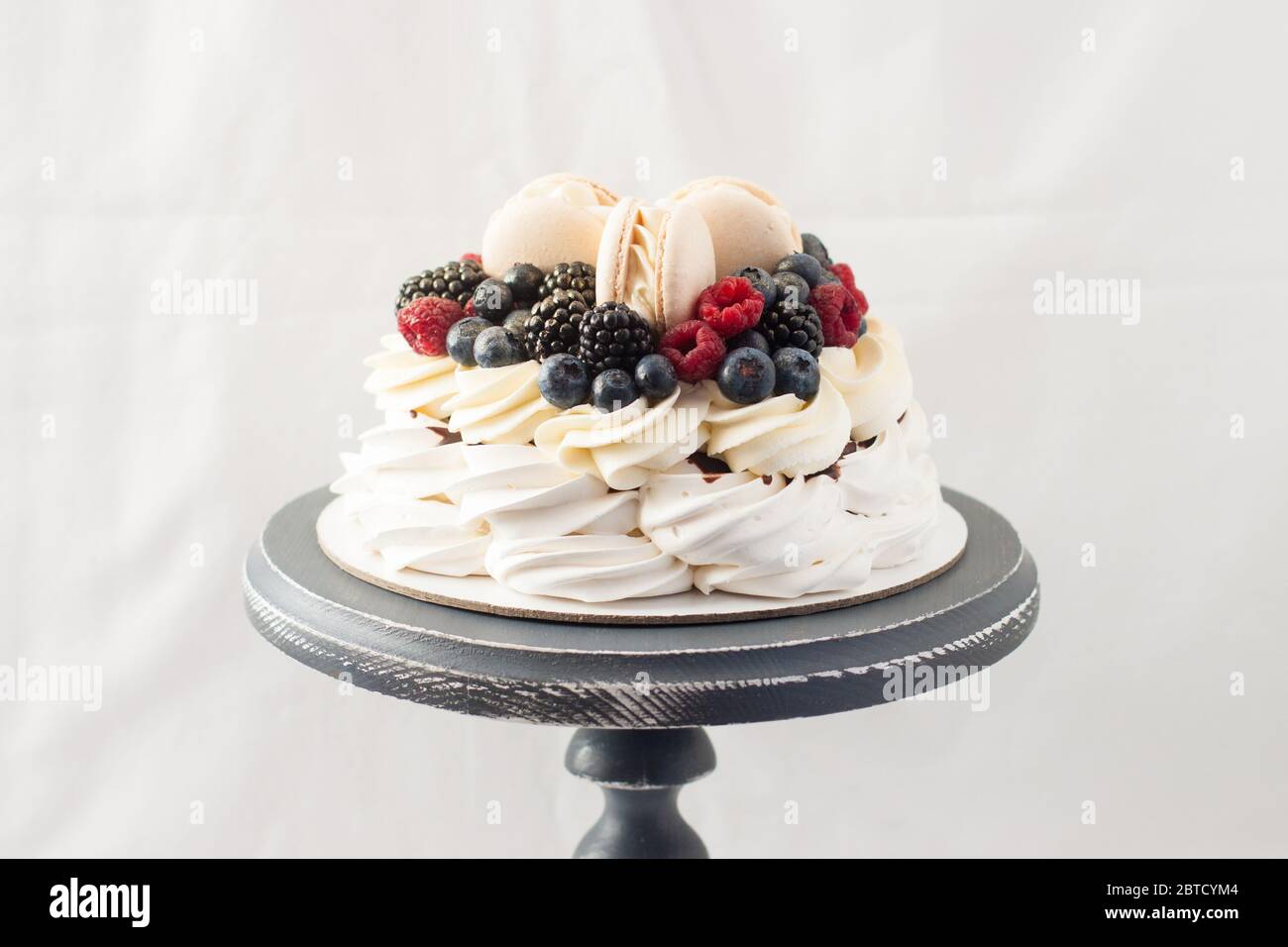 Pavlova Cake With Meringue Whipped Cream Adn Fresh Berries Decorated With Vanilla Macaroons Plain White Background Copy Space Stock Photo Alamy