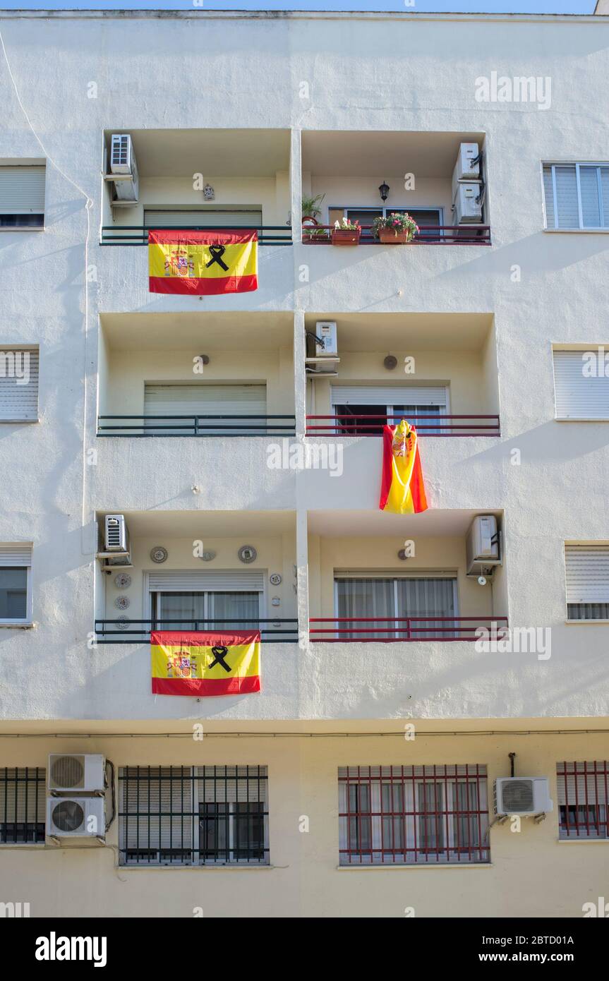 Badajoz, Spain - May 18th 2020: Spanish flags with a black ribbon hangs over balconies. Tribute to Covid-19 victims Stock Photo