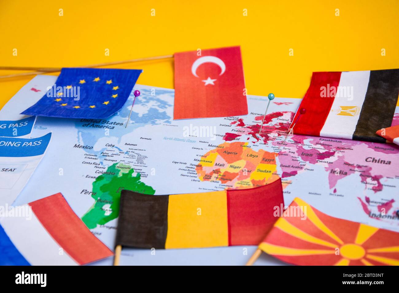 Flags from different countries and boarding pass over world map Stock Photo