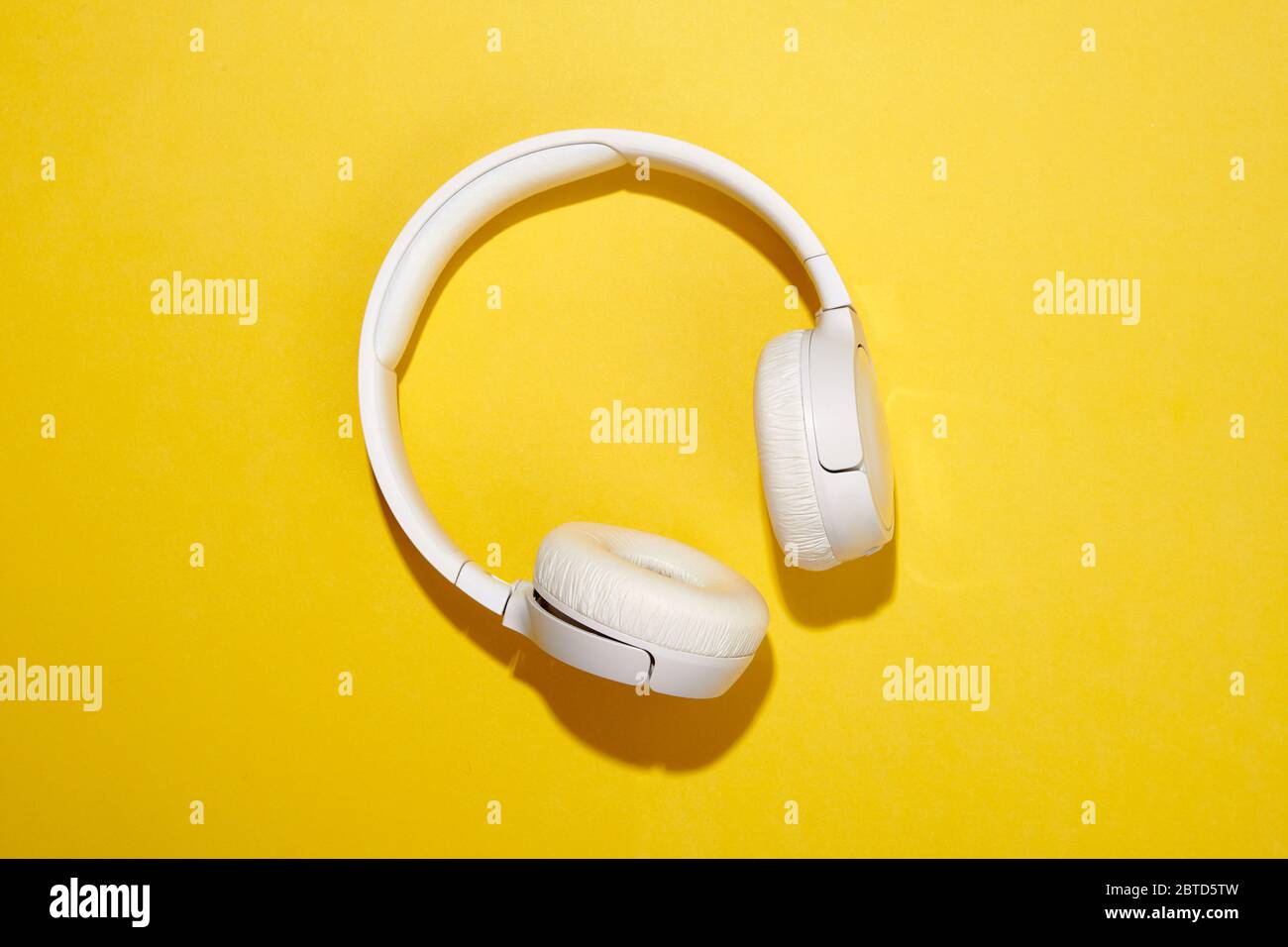 Pair of white stereo headphones on a yellow background with shadow place in the center Stock Photo