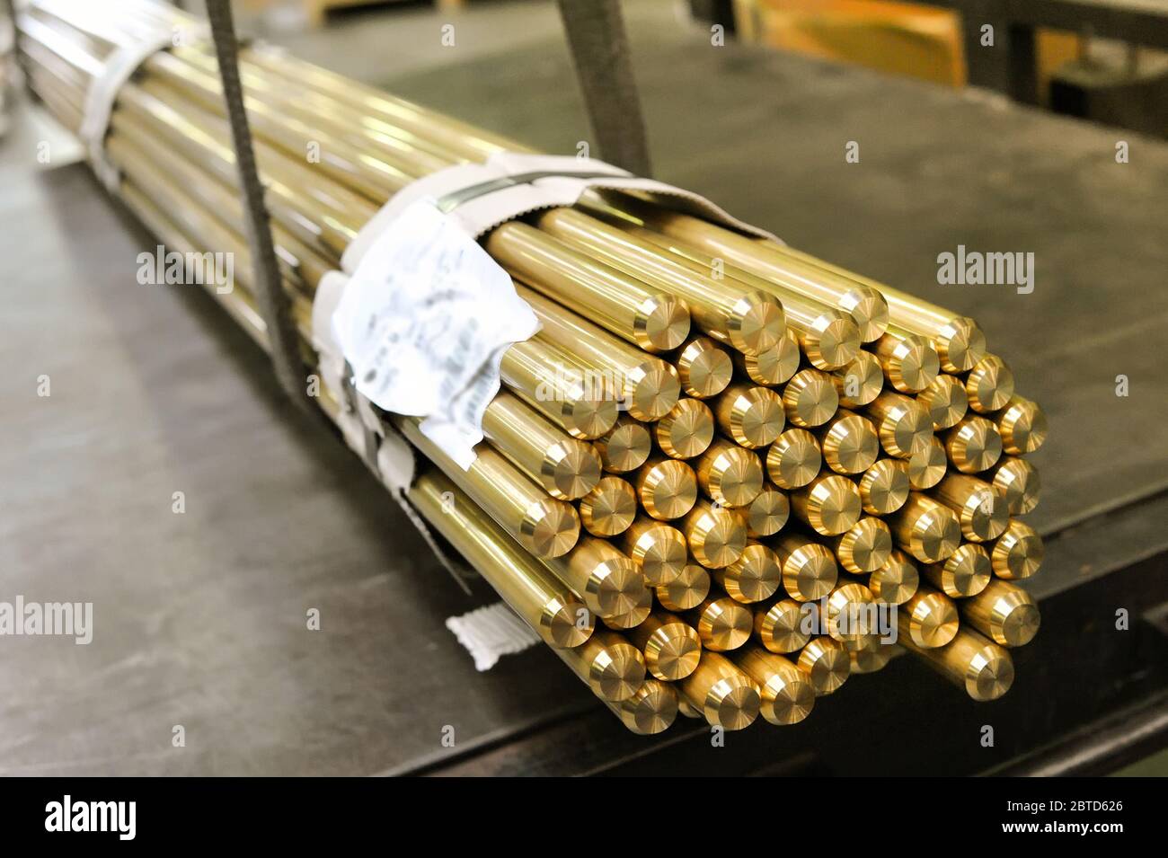 Bundle of bright shiny industrial brass rods in a market tied together with product information slip in close up on the ends Stock Photo