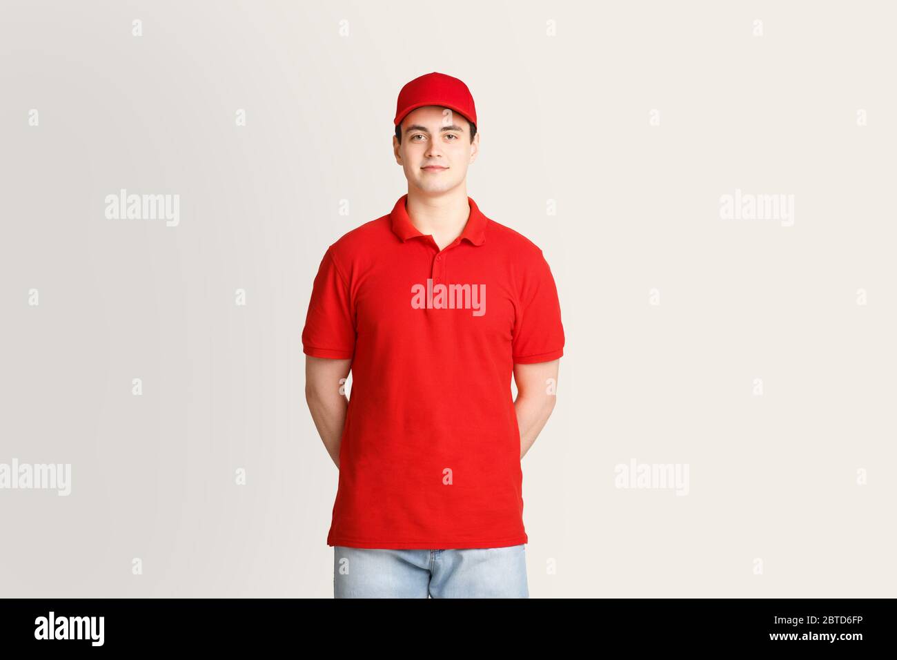 Modern post and package delivery. Courier in red uniform on light background Stock Photo