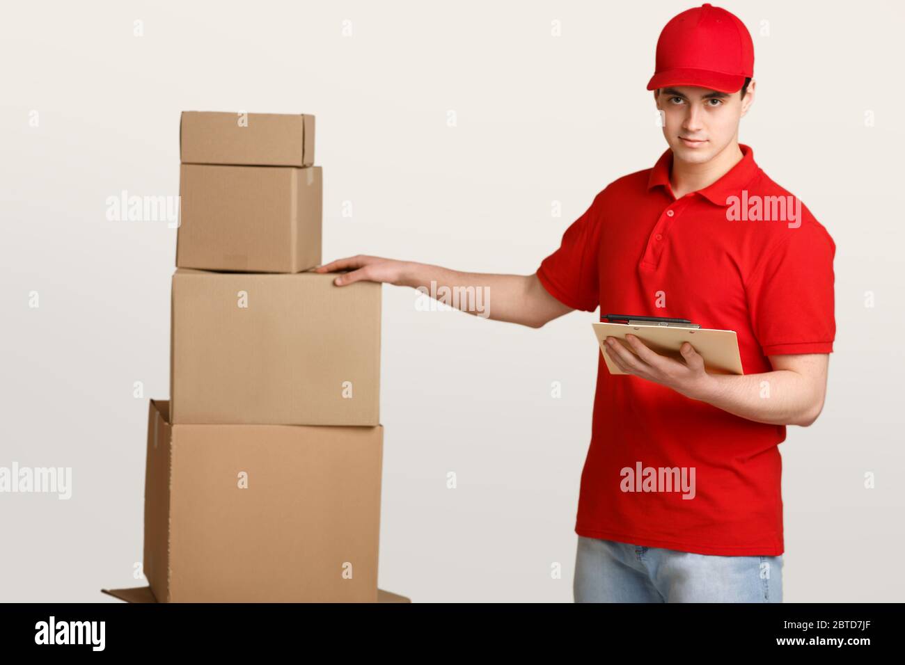 Reliable delivery. Courier checks parcels in warehouse with tablet Stock Photo