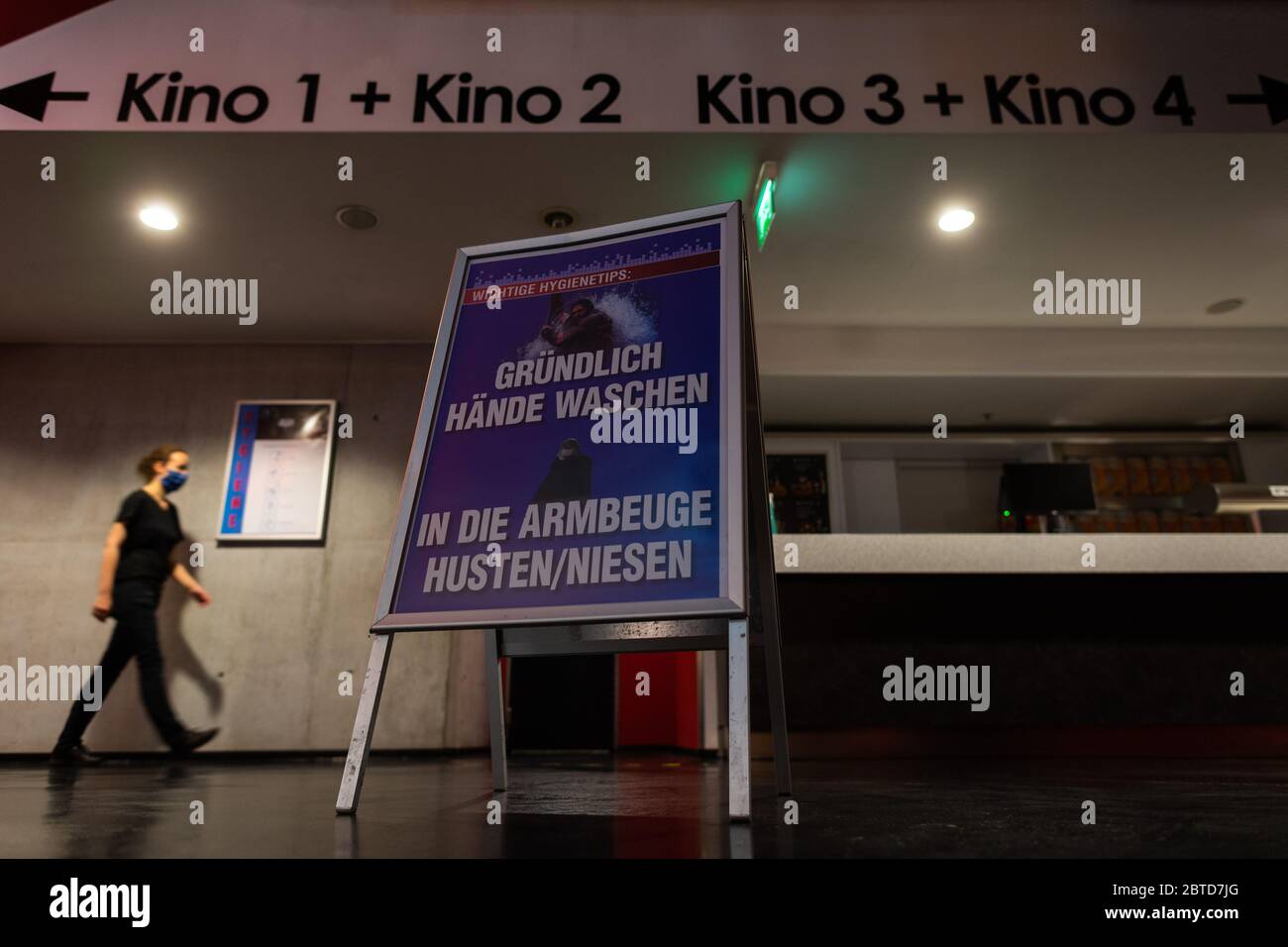 Dresden, Germany. 22nd May, 2020. A woman with a face mask walks behind a sign with hygiene instructions in the cinema Ufa-Kristallpalast in the inner city. As the first big cinema in the city, the Ufa-Palast was allowed to reopen after the Corona-Lockdown. (to dpa 'With popcorn, without mask: How can a visit to the cinema look like now?') Credit: Robert Michael/dpa-Zentralbild/dpa/Alamy Live News Stock Photo