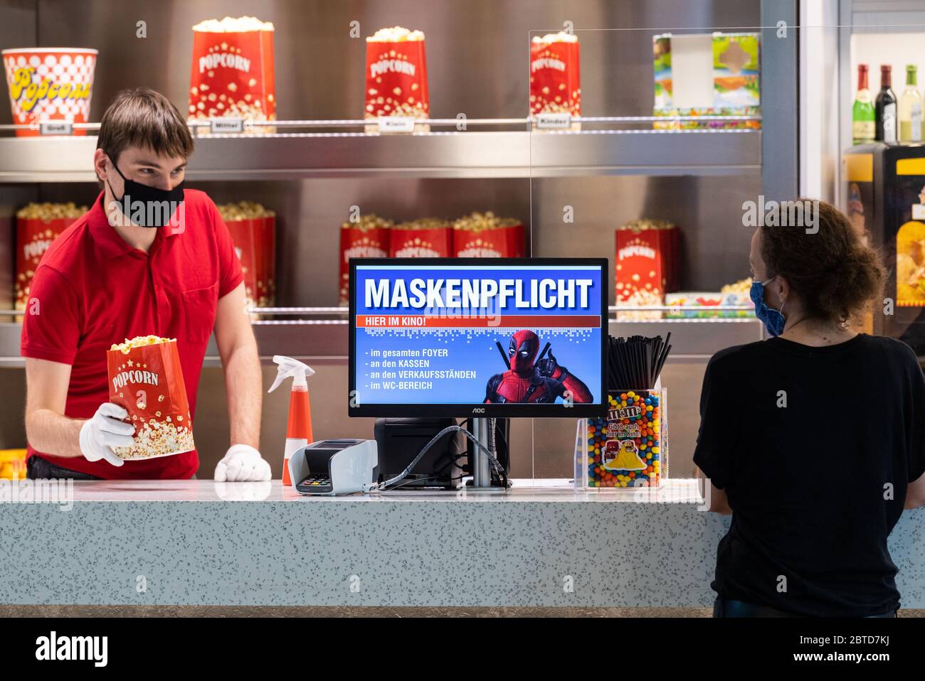Dresden, Germany. 22nd May, 2020. On a screen in the foyer of the Ufa-Kristallpalast cinema in the inner city, the obligation to wear masks is pointed out, while an employee sells popcorn at the counter. As the first big cinema in the city, the Ufa-Palast was allowed to reopen after the Corona lockdown. (to dpa 'With popcorn, without mask: How can a visit to the cinema look like now?') Credit: Robert Michael/dpa-Zentralbild/dpa/Alamy Live News Stock Photo