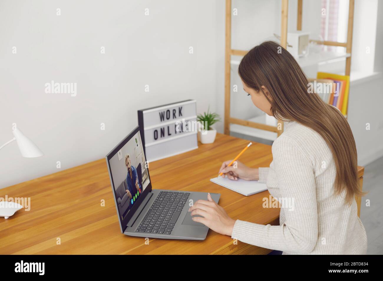 Work online. The remote employee has a video chat call using a laptop on a desk not in the workplace at home. Stock Photo