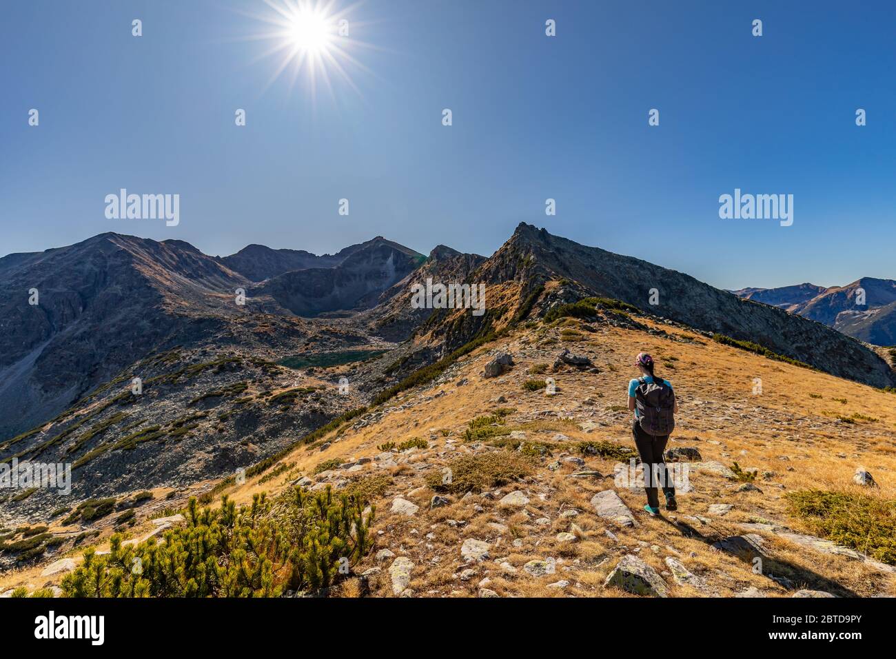 Woman hiking in Rila mountains on the way to Musala peak in Bulgaria on a sunny day in Autumn, Fall Stock Photo