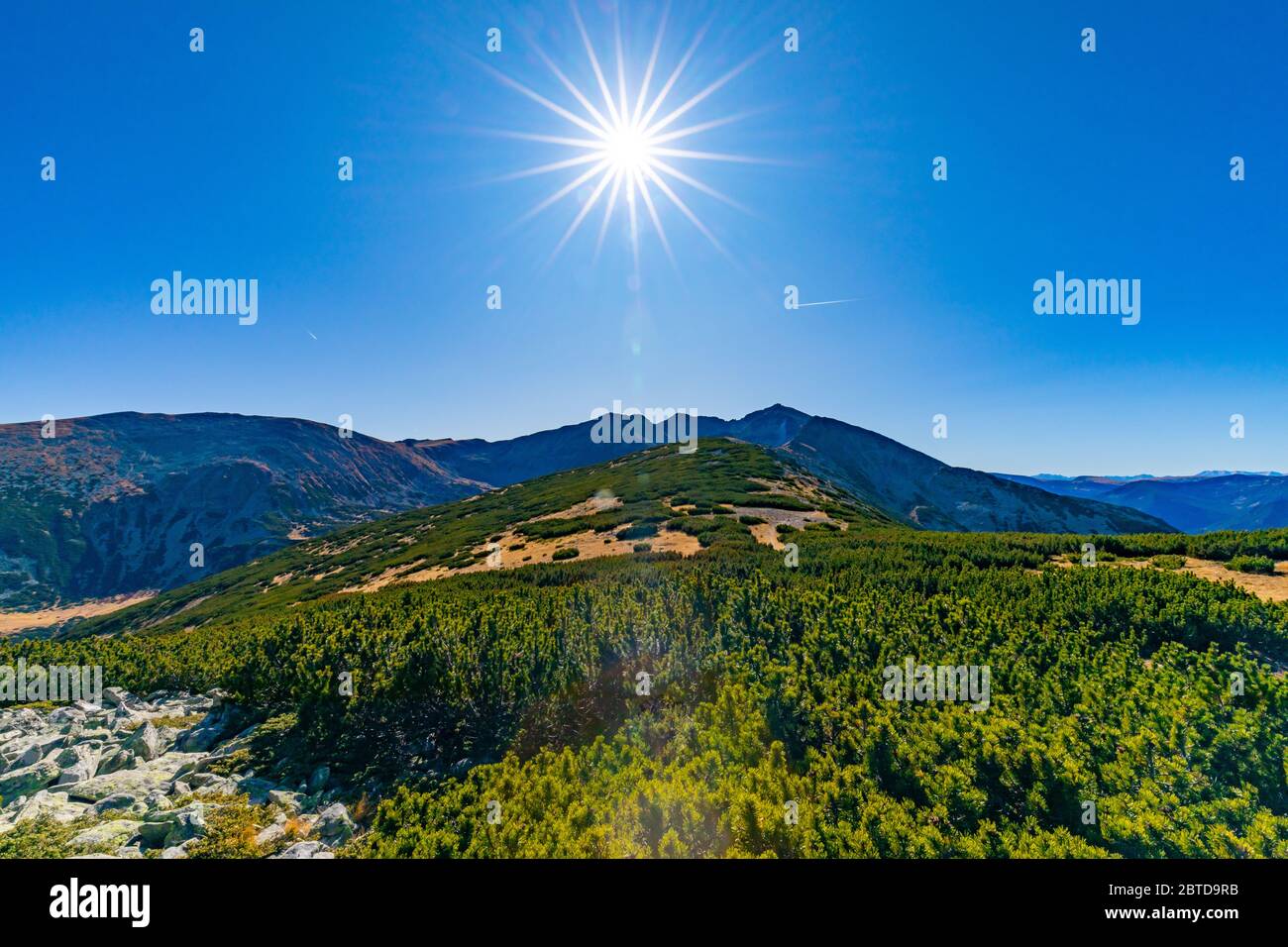 Sun on the blue sky over the mountains overlooking Musala in Rila Region, Bulgaria Stock Photo