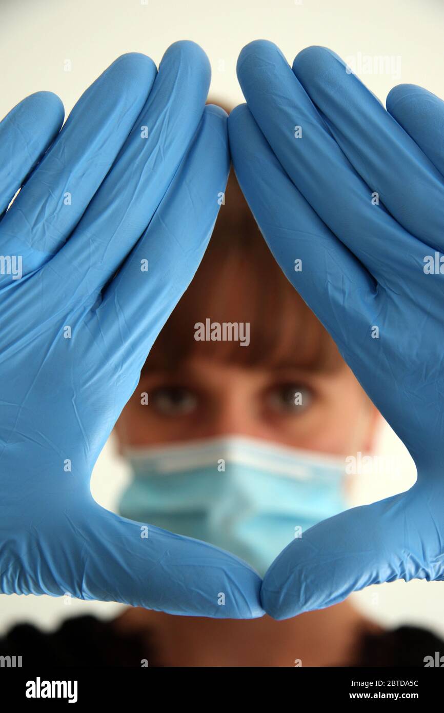 Female with surgical gloves protecting masked face. Stock Photo