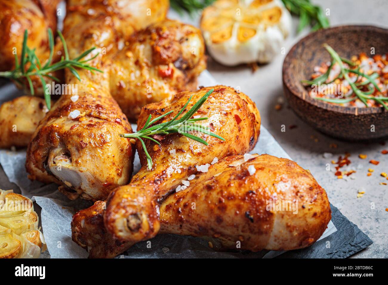 Fried spicy chicken legs with herbs and garlic on black slate, dark