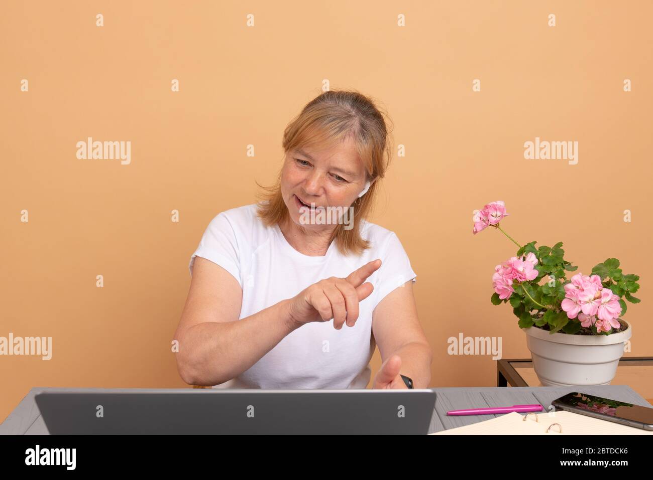 Happy middle age woman in headphones speaking looking at laptop, elderly student talking by video conference call, female teacher trainer tutoring by Stock Photo