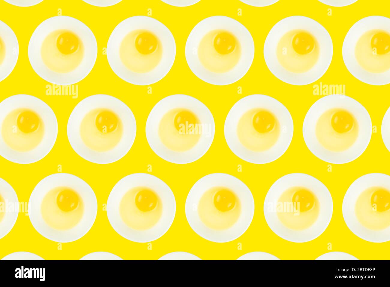 Pattern of raw eggs in bowls on yellow background. Healthy food and cooking at home concept. Stock Photo