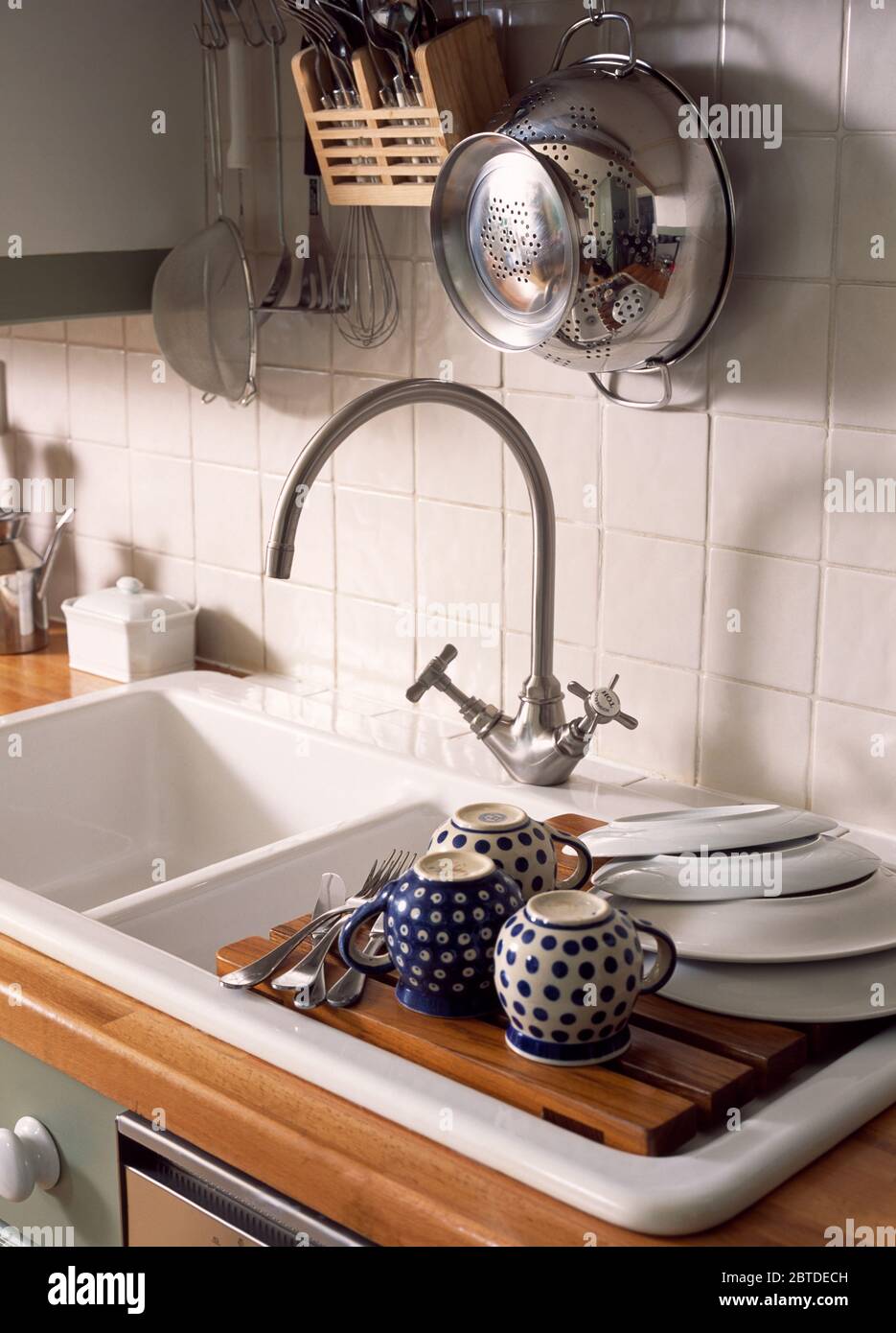 Blue+white spotted Polish cups beside sink with chrome tap Stock Photo