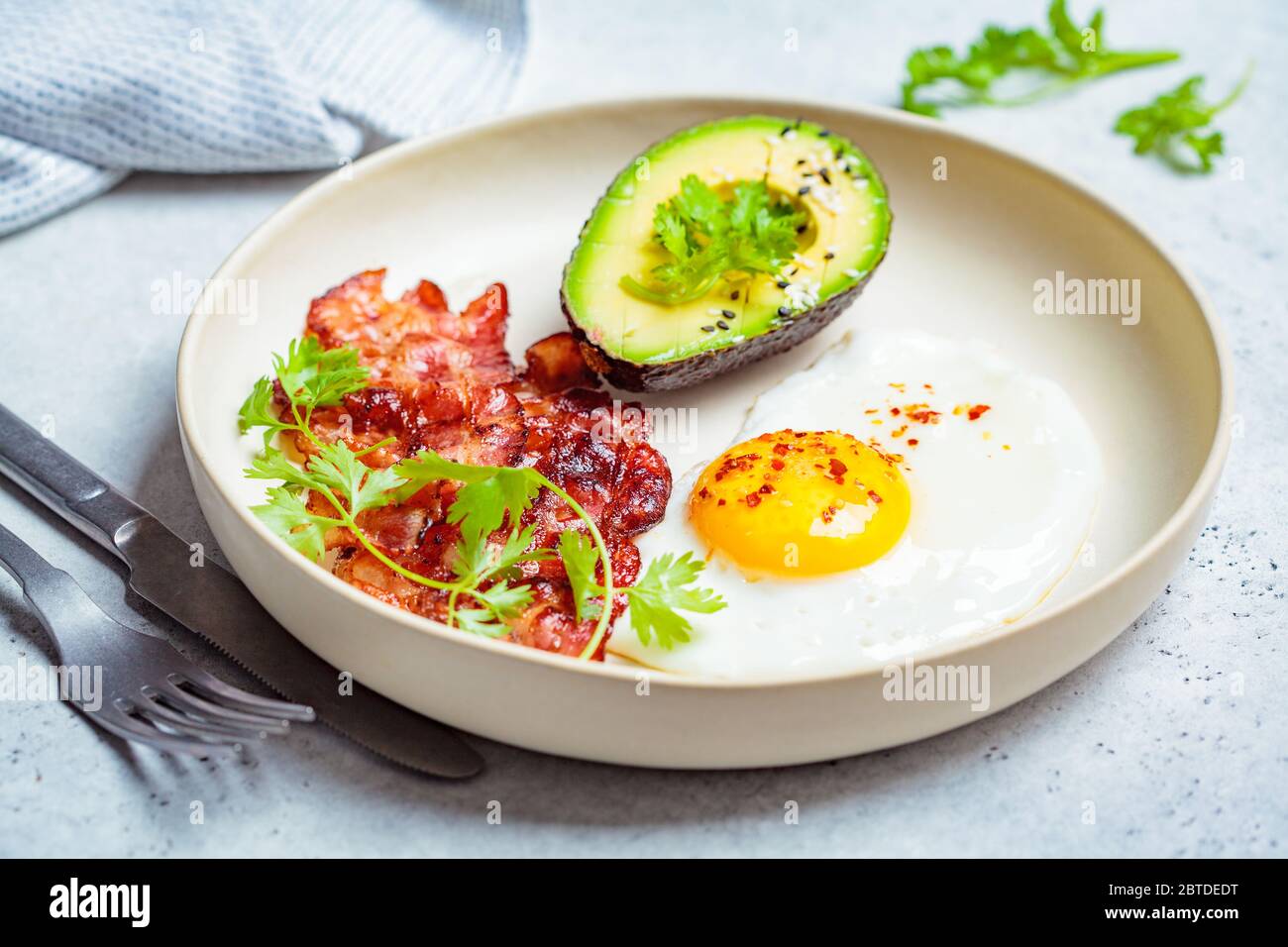 Keto breakfast - fried egg, avocado and bacon in a white plate. Keto diet concept. Stock Photo