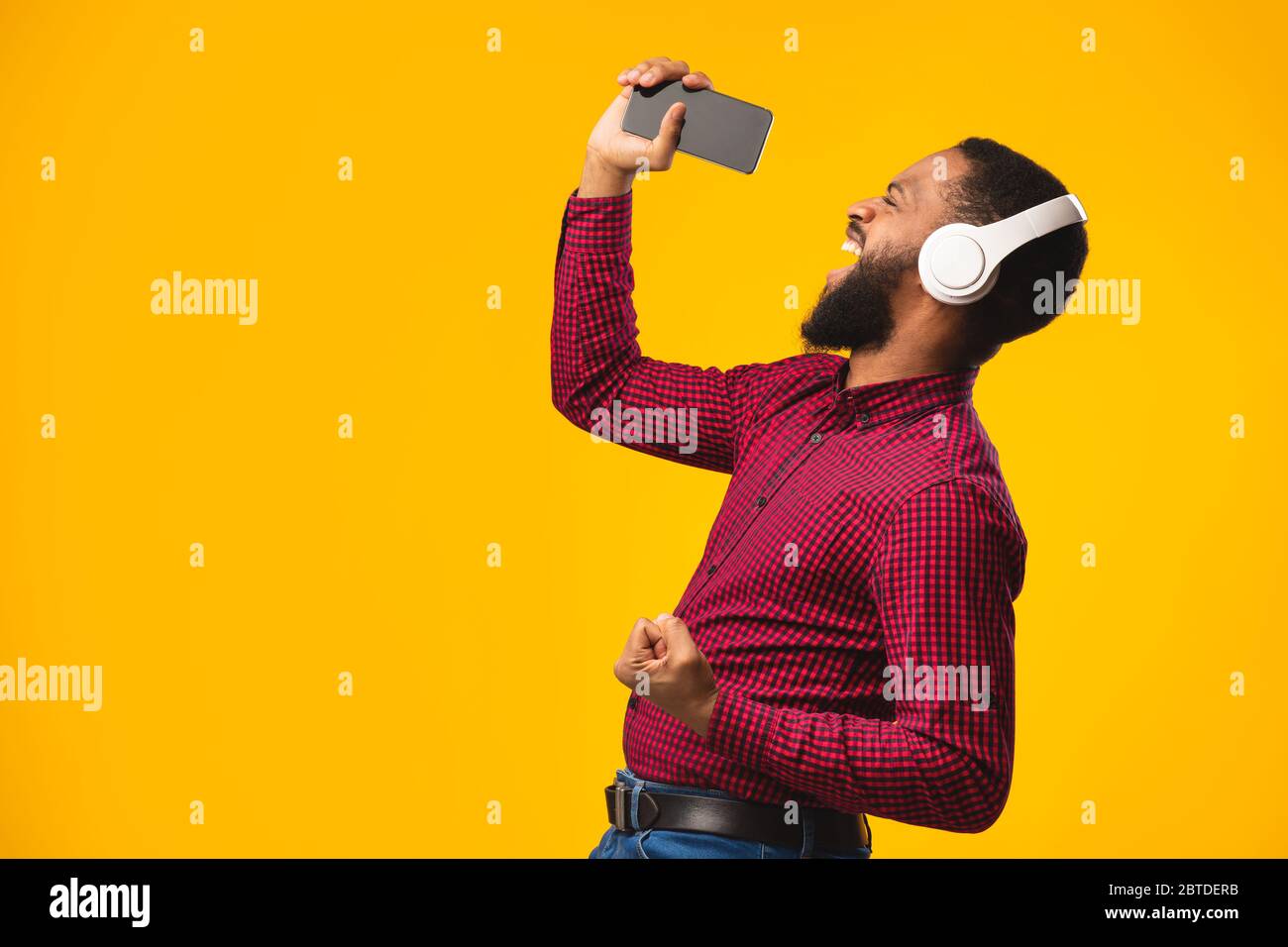 Afro man singing using smartphone as microphone Stock Photo