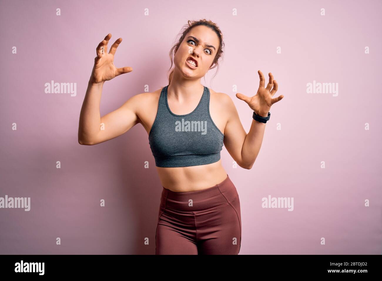 Young beautiful blonde sportswoman doing sport wearing sportswear over pink  background Shouting frustrated with rage, hands trying to strangle, yellin  Stock Photo - Alamy