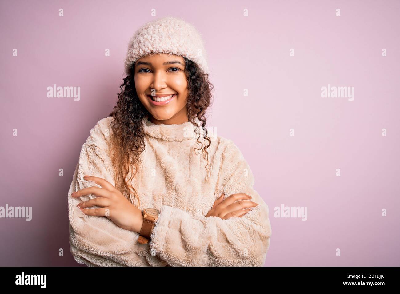 Beautiful woman with curly hair wearing casual sweater and wool cap ...